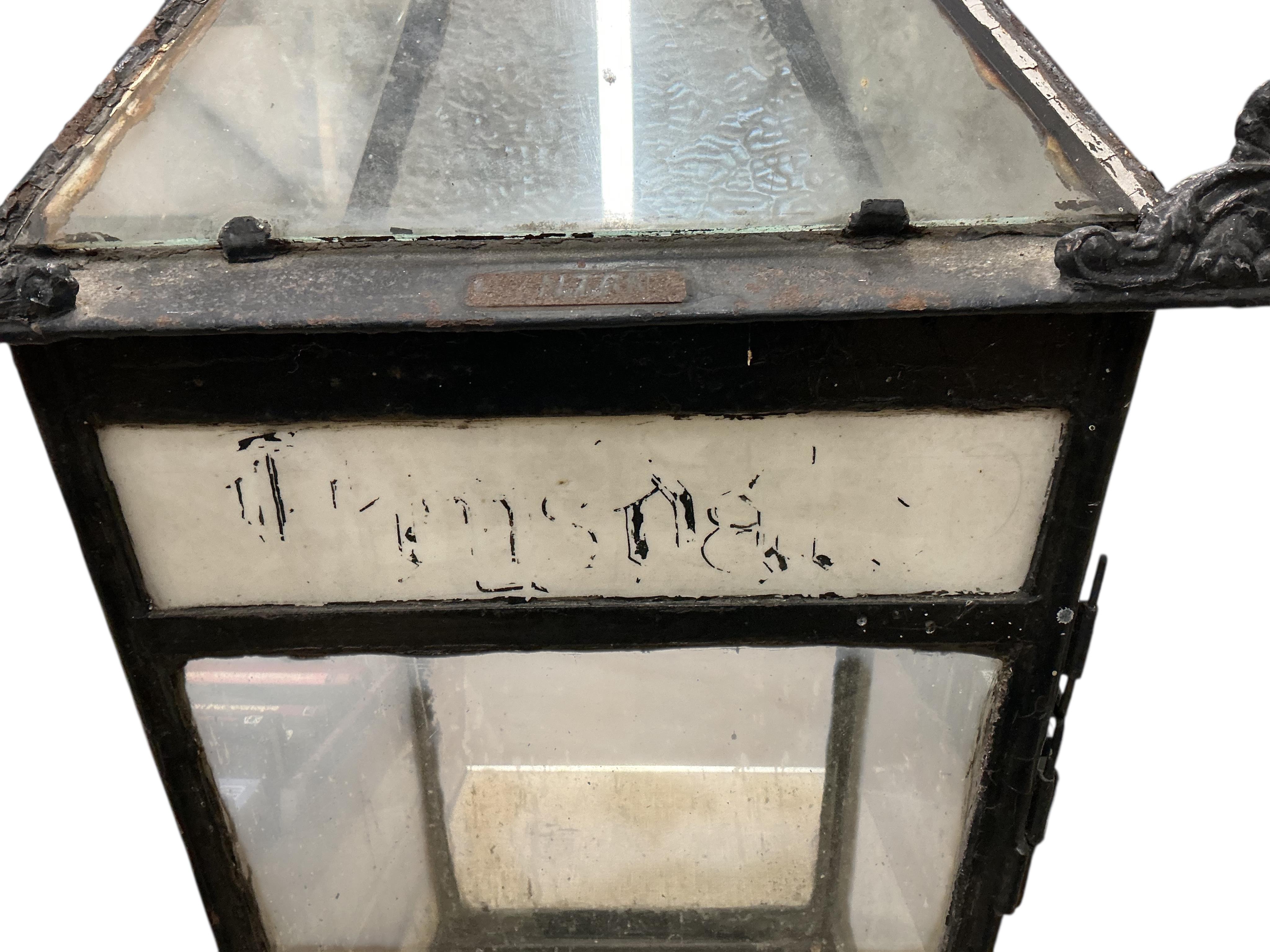 A glass and steel railway station lantern with an opaque glass panel showing the remains of a painted possible station name, missing the burner etc., 80cm high, 40cm wide